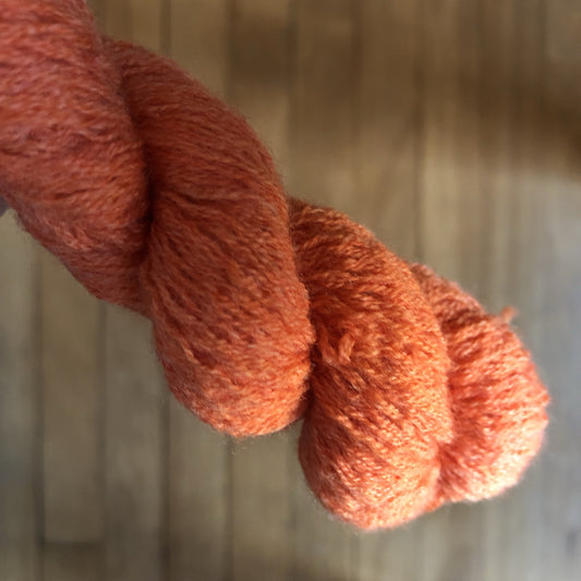 Up close shot of the bright orange thin yarn.