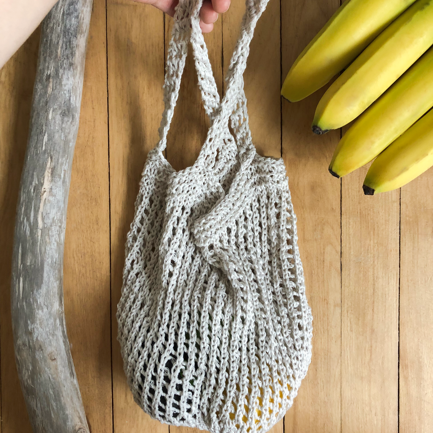 A salt of the earth produce bag size large holding avocado, kiwis, lemon, and mango. The holes in the sides of the bag stretch to hold the fruit inside.